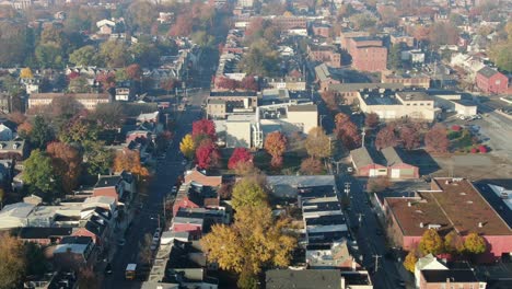 Aerial-tilt-down-of-school-bus-driving-through-urban-city-in-USA-during-morning-magic-hour