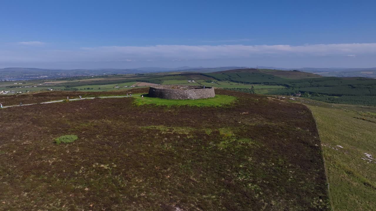 Grianan of Aileach, County Donegal, Ireland, June 2023. Drone aerial ascent atop a hill overlooking the Gaelic Greenan Stone Fort surrounded by scenic countryside on a sunny afternoon.