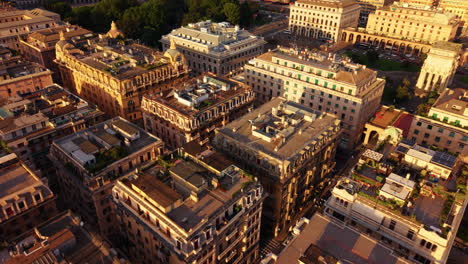 drone in full top-down move above genoa rooftops, showing old buildings with green terraces, leading to piazza della vittoria and its arch at sunset