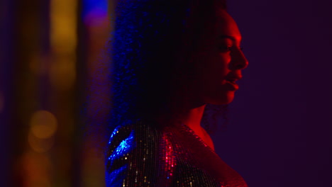 young woman having fun in nightclub or bar shot through tinsel curtain in foreground 1