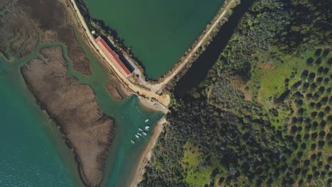 edge of artificial fish farm pond flowing out to the river topdown aerial