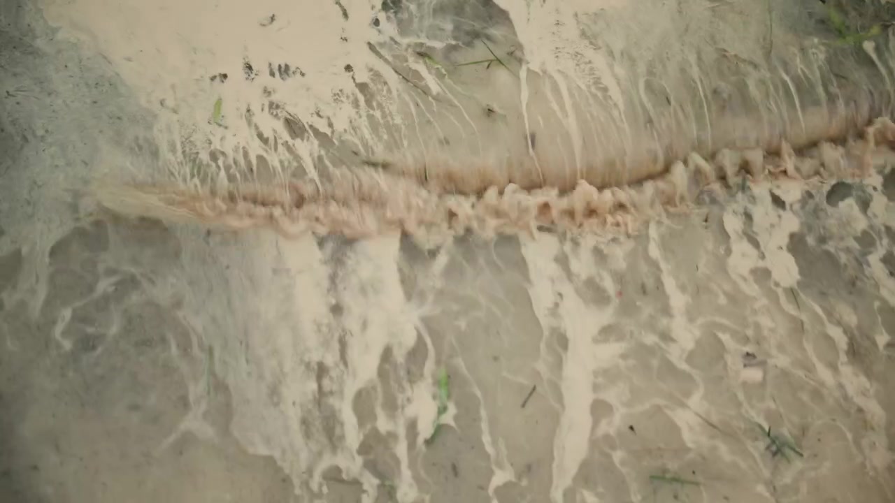 Skummende bølge fra Middelhavet der skyller ind på en sandstrand