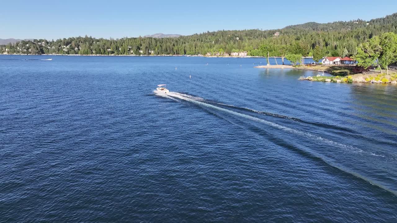 siguiendo un barco a alta velocidad en el lago arrowhead california siguiendo el bote de disparo creando una gran estela en el agua con la gente disfrutando del sol de verano en el agua azul siguiendo la antena