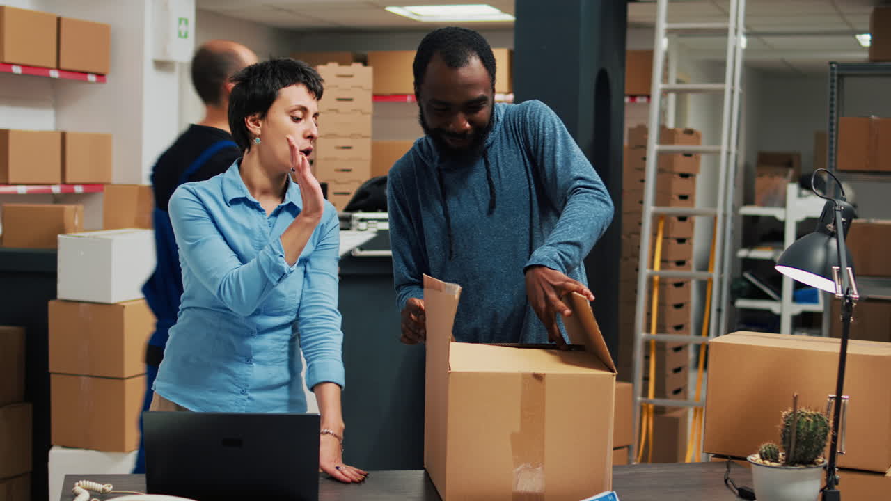 People working in a warehouse with boxes and a laptop