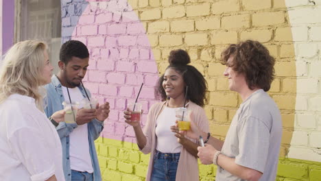 cheerful  young friends toasting their drinks on a colourful street