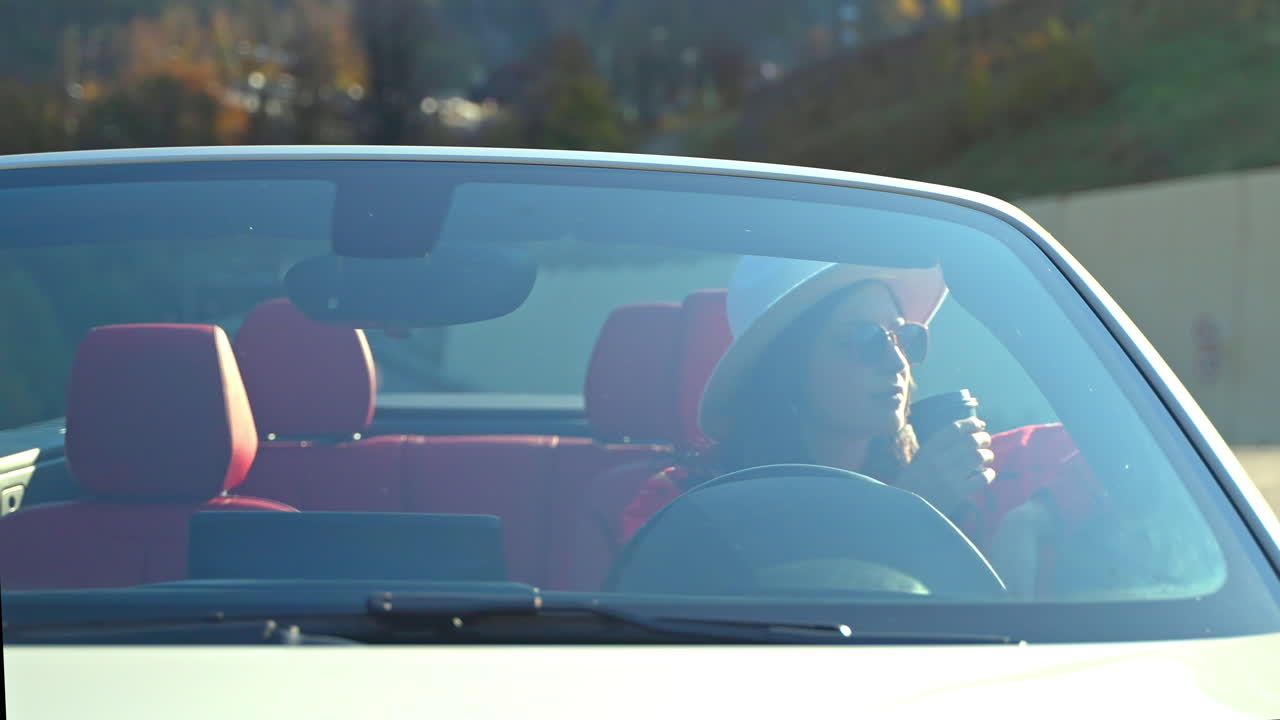 커버티블을 운전하고 커피를 마시고 있는 여자