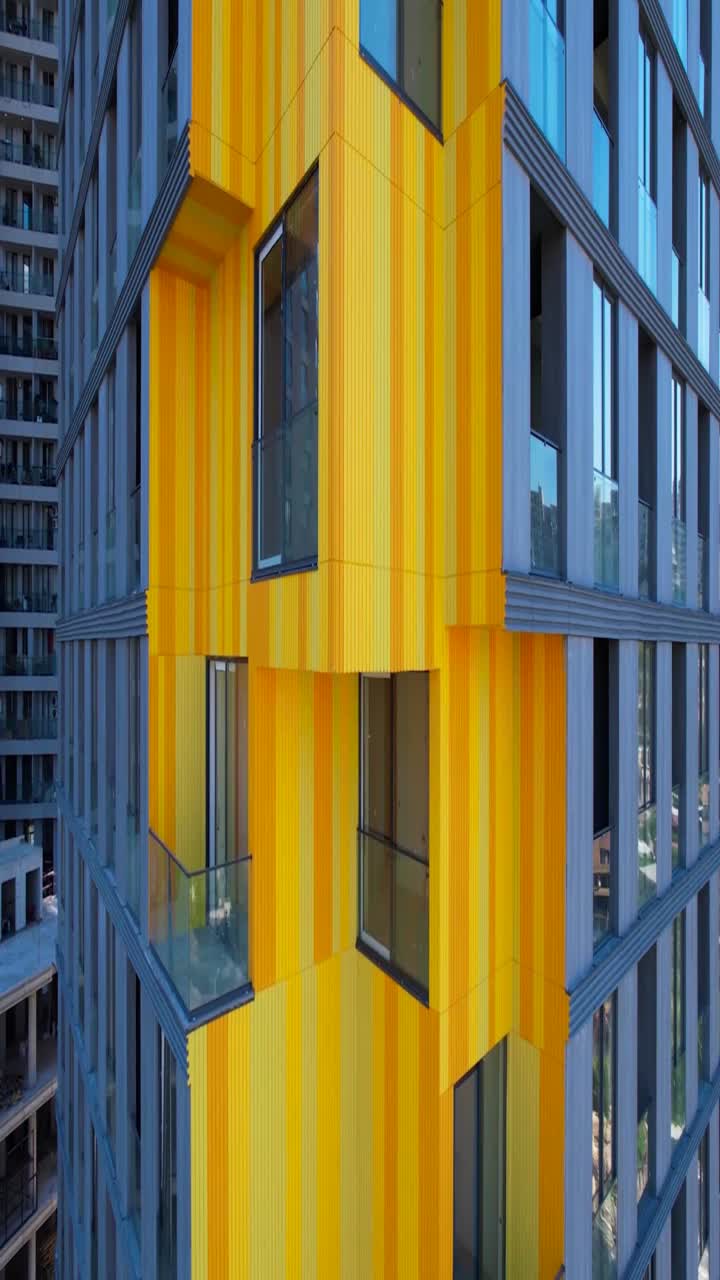 Panoramica verso l'alto di un edificio moderno con facciata gialla e arancione