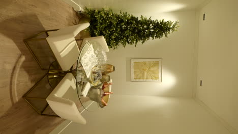 wide vertical shot of glass table with drinks and christmas tree, handheld