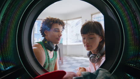 closeup couple washing clothes in public launderette. smiling friends watching