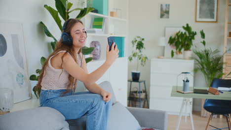 mujer sonriente en llamada de video con un amigo mientras está sentada en el sofá