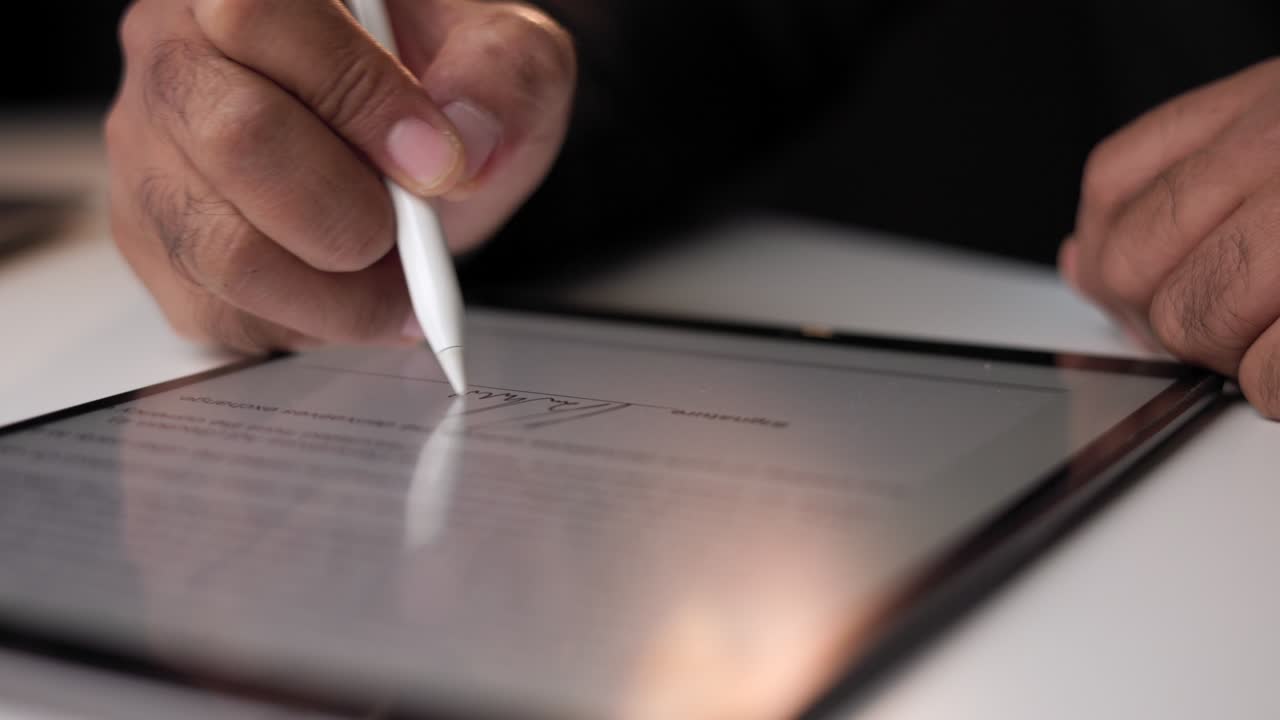 Close up businessman hand working electronic Signature on Tablet by Stylus at night. Write business agreement of contract. Man signing contract on tablet. Business and technology concept.