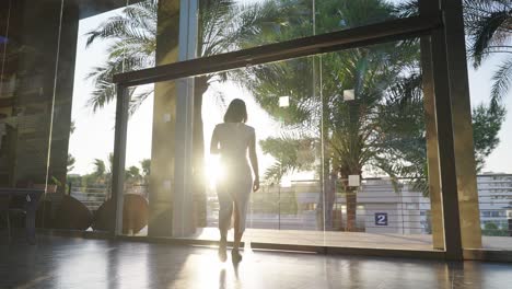woman walking through glass doors at sunrise