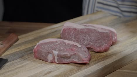 bistec de carne de res cruda preparado y marinado con sal para asar en una tabla de madera
