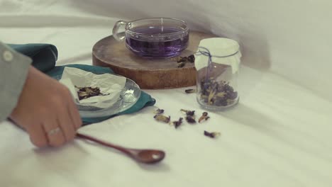 stirring a cup of butterfly tea at home, showing the concept of wellness, wellbeing and winter aesthetic