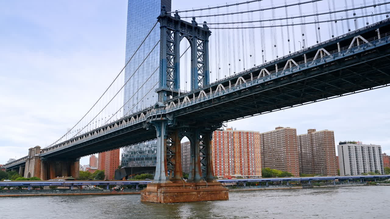 Spectacular Manhattan Bridge from the East River waterscape. Glass skyscraper at backdrop