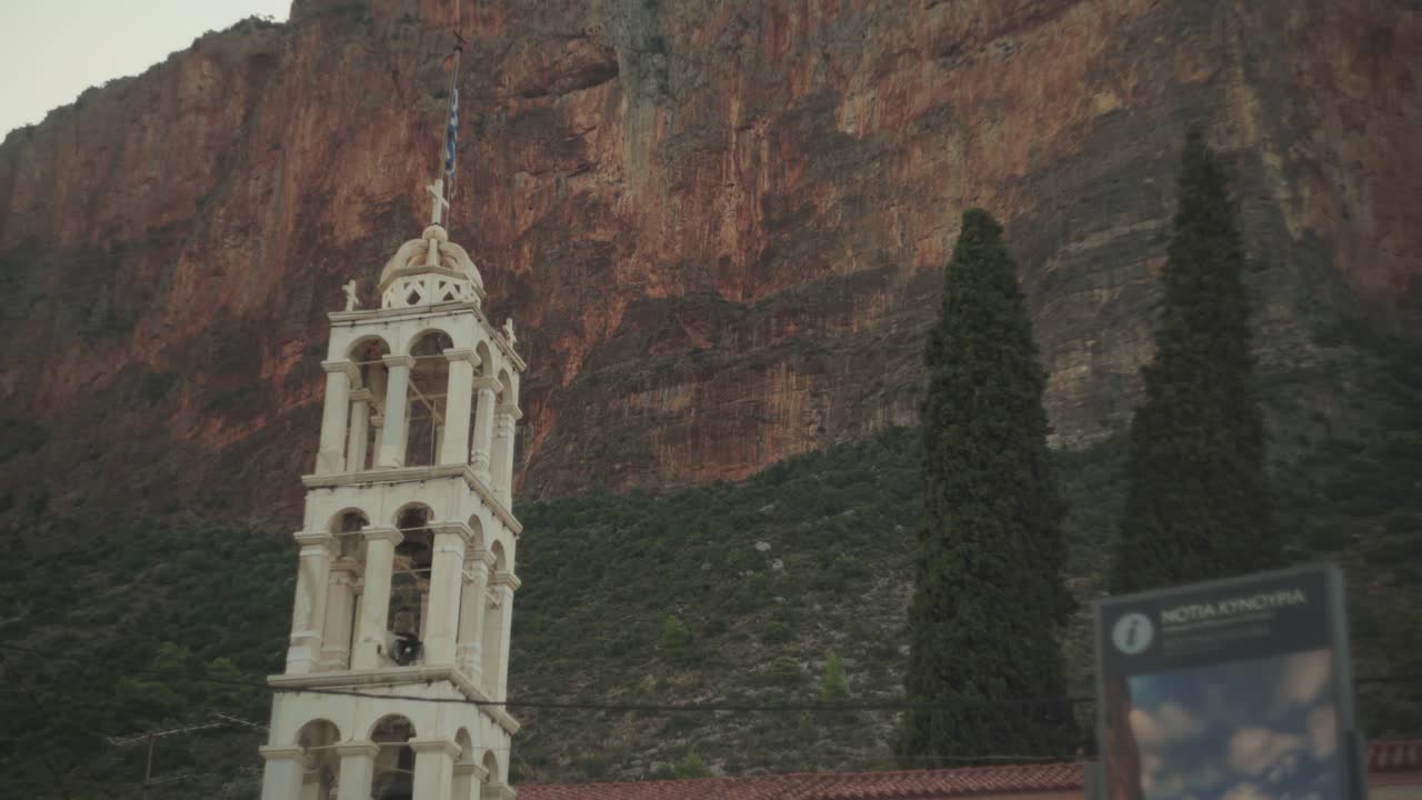vista estática hacia arriba del campanario de un monasterio o una catedral contra acantilados rocosos dentados en leonidio, grecia
