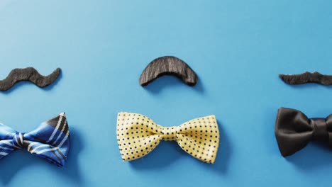 Video-of-three-varied-false-moustaches-and-bow-ties-on-blue-background-with-copy-space