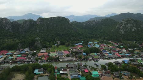 Aerial-footage-sliding-to-the-right-revealing-a-bridge,-river,-fishing-village,-mountains-and-rainclouds