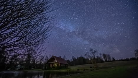 Nachthimmel-Sternzeitraffer-Auf-Dem-Land-Mit-Einem-See-Und-Einem-Kleinen-Haus