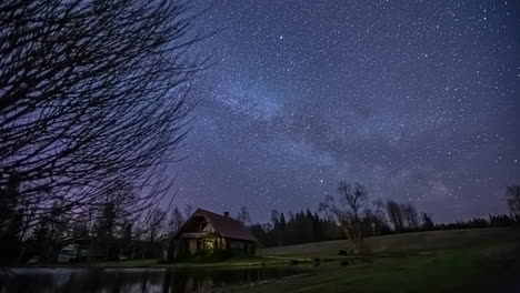 lapso de tiempo estrella del cielo nocturno en el campo con un lago y una pequeña casa