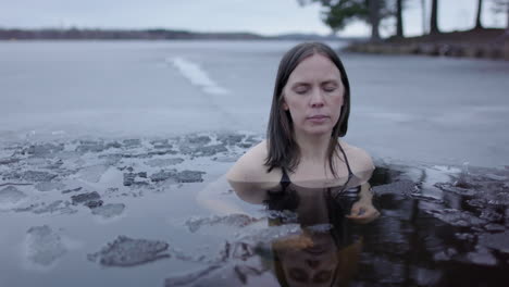 an ice bathing woman puts her hands together and calmly breathes, slider shot