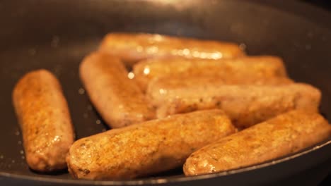 fake meat sausages in oil cooking on gas stove