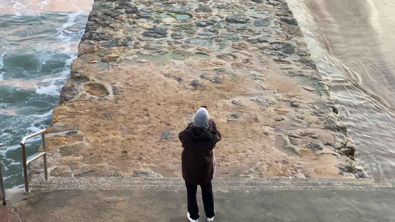 hombre tomando una foto panorámica con el teléfono en una playa al atardecer
