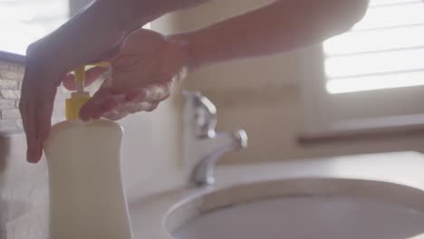 Mid-section-of-woman-using-hand-wash-to-clean-her-hands