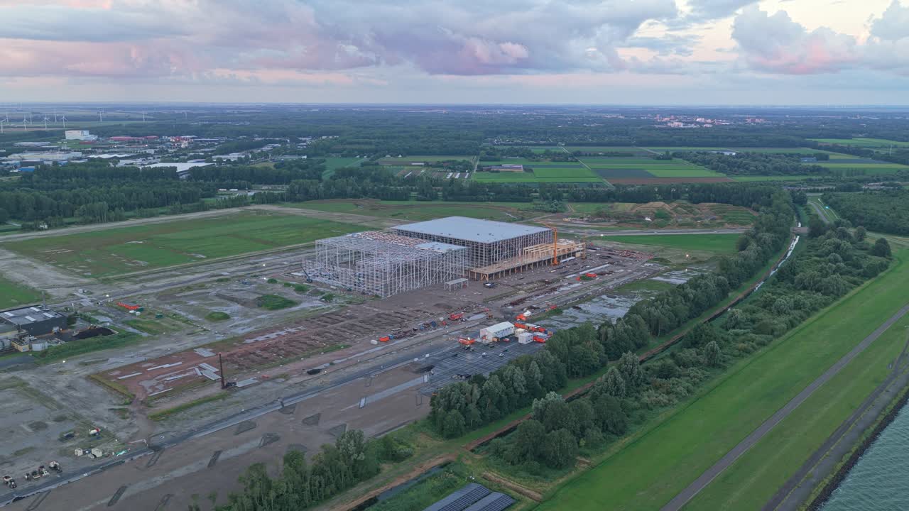 Alba in un sito industriale, gru che assembla il tetto per un nuovo centro di distribuzione