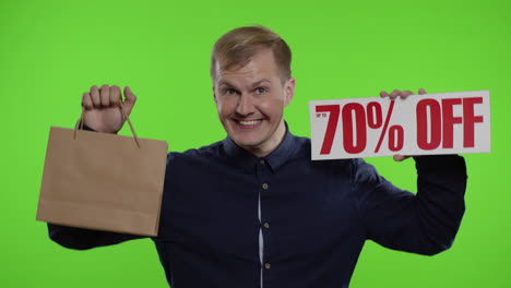 happy man showing shopping bags and up to 70 percent off inscriptions signs. good holiday discounts