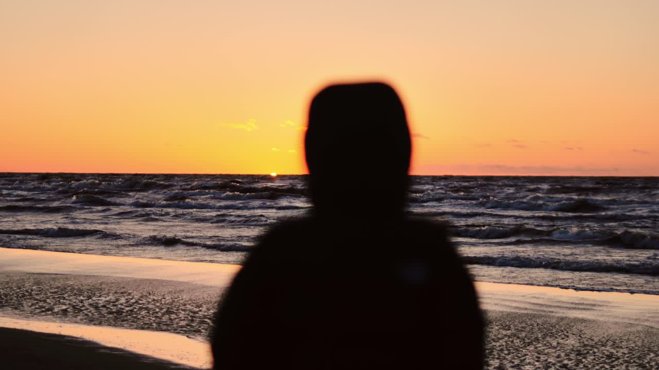 Peaceful beach scene with changing focus from sun to silhouette of calm observer