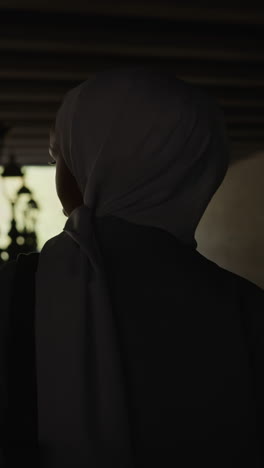 arabic woman silhouette looks at river walking along shady riverside under bridge backside view slow motion. muslimah tourist in city. visiting landmarks