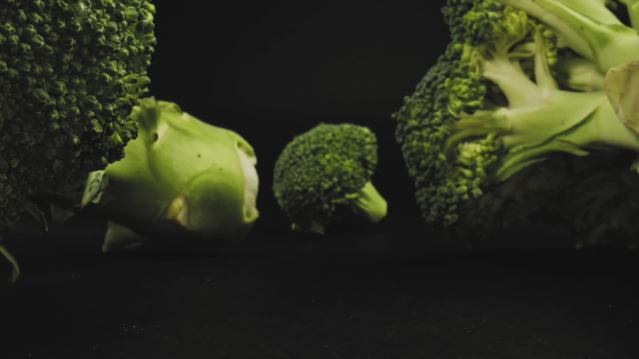 Macro push in close up of broccoli in a black background with a probe lens
