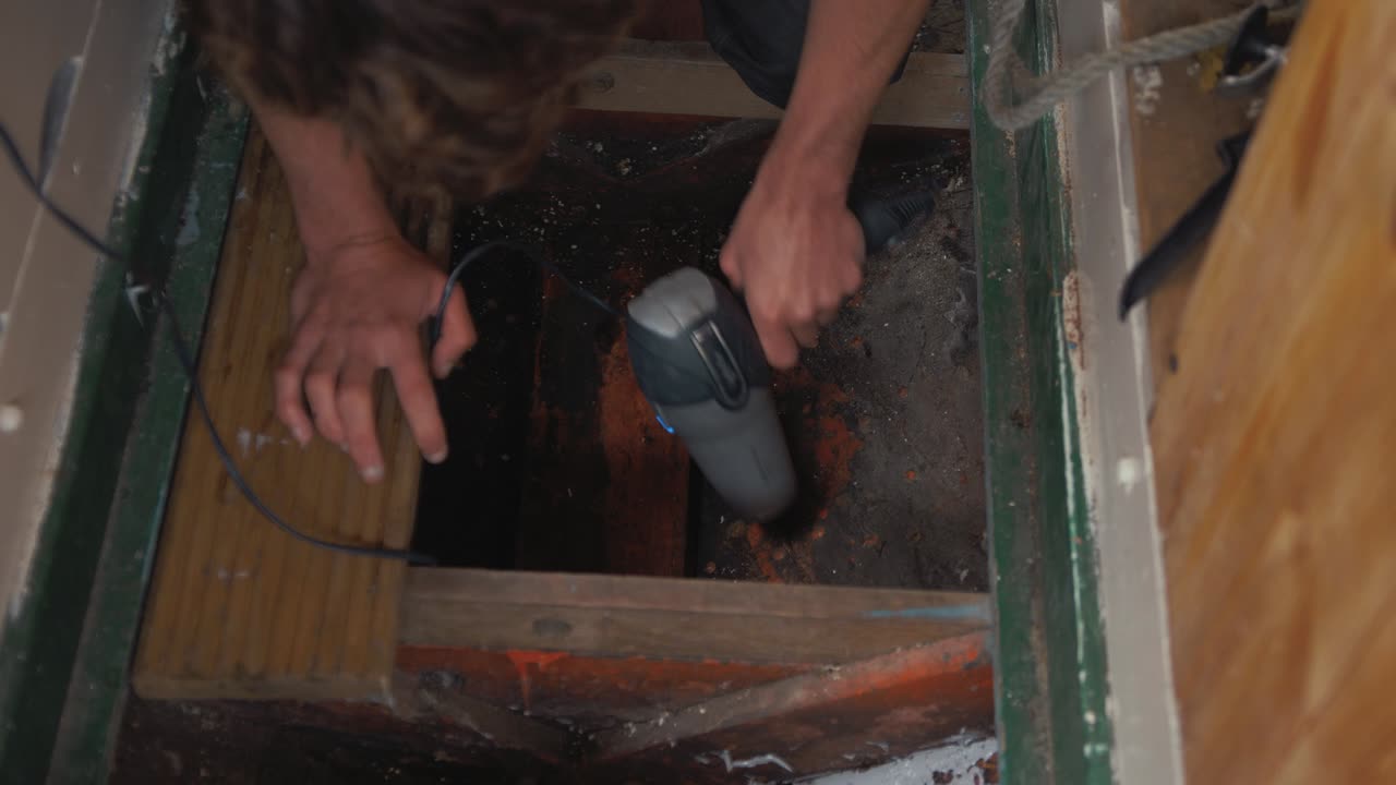 Man drying bilge of old wooden boat to check for water leaks