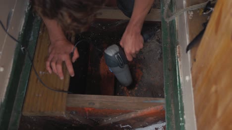 hombre secando sentina de un viejo barco de madera para comprobar si hay fugas de agua