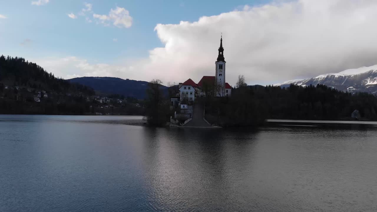 Aerial view of Island in Bled Lake. Exciting autumn scene of Bled lake at the sunset. Charming autumn panorama landscape of island with church rounded colorful trees in the middle of Bled lake.