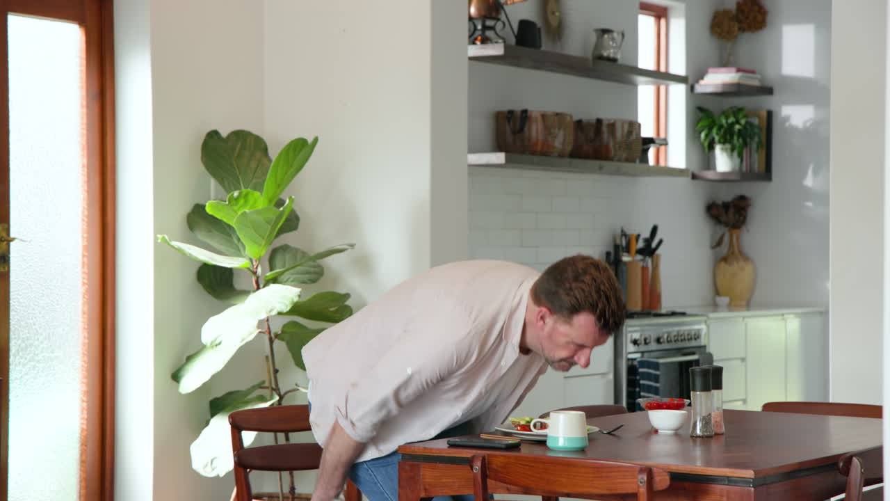 Senior man enjoying breakfast at home, sitting at kitchen table