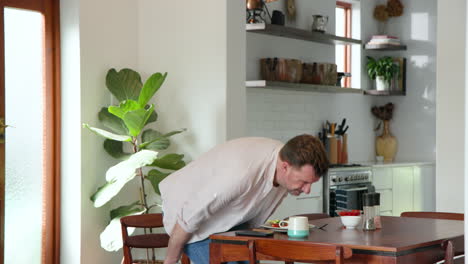 senior man enjoying breakfast at home, sitting at kitchen table