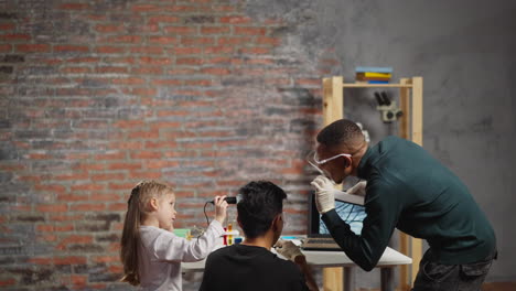 el asistente de laboratorio negro ayuda a la niña a escanear el cabello del padre.