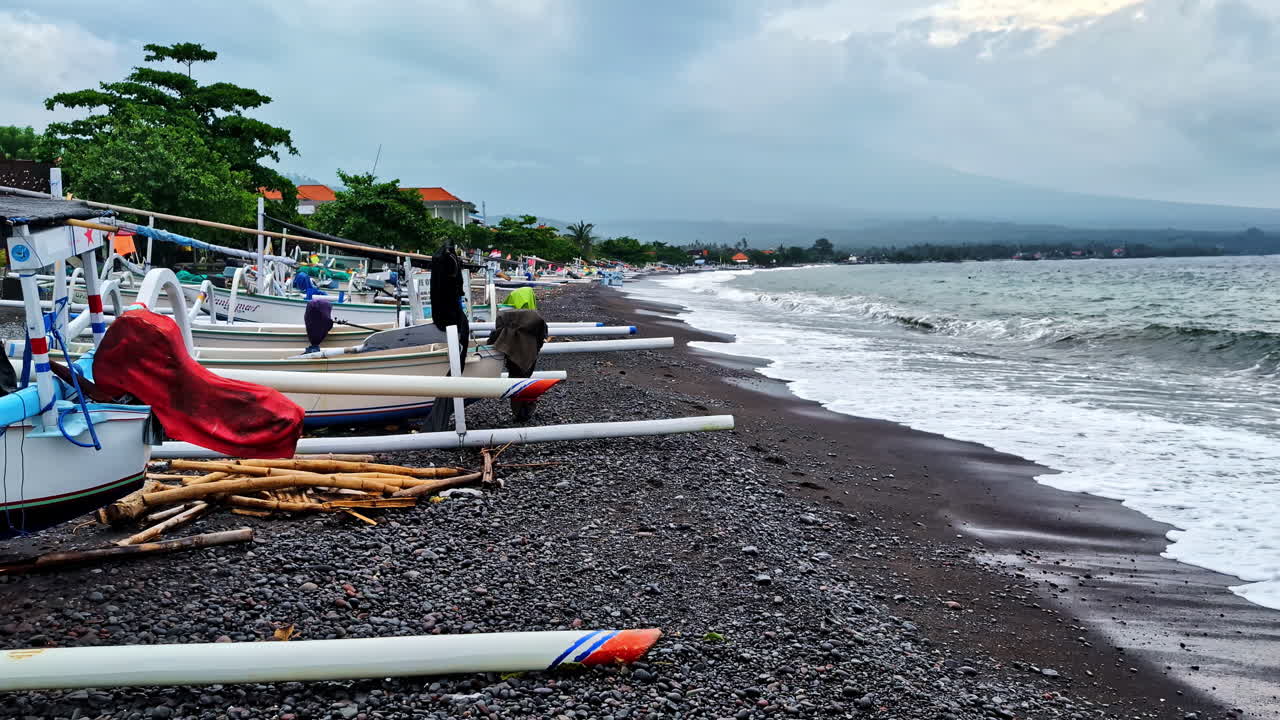 Capturing of dark, pebbled beach with several fishing boats lined up on shore