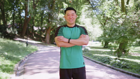 portrait of happy japanese sporty man athlete healthy lifestyle posing looking at camera in park