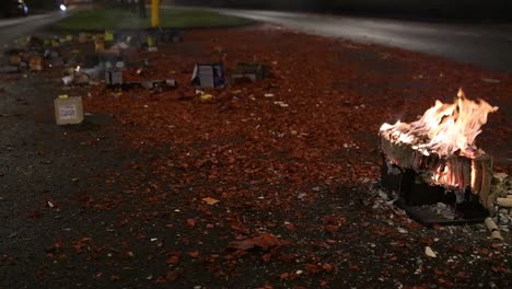 fuego en cámara lenta que arde de fuegos artificiales en una carretera cubierta de escombros por la noche