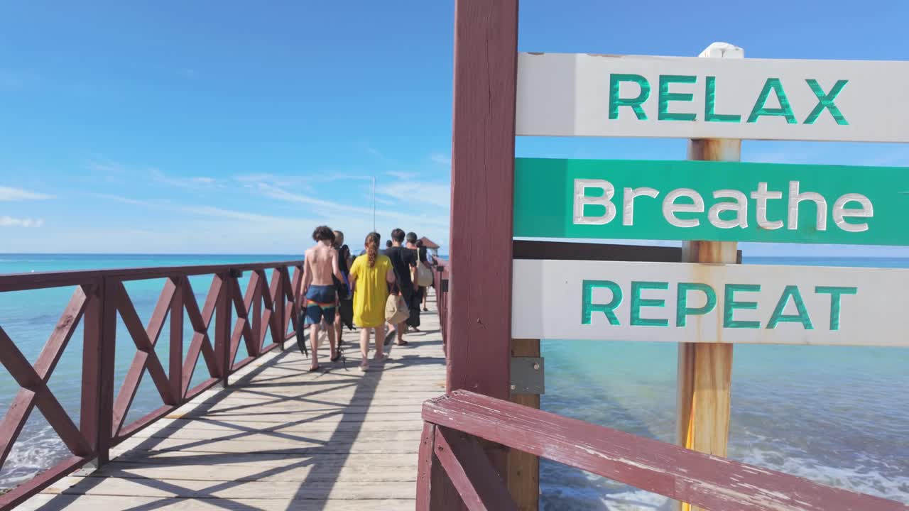 Sign with inscription: relax, breathe, repeat. Pier of Playa Dominicus beach, Bayahibe in Dominican Republic. Slow-motion