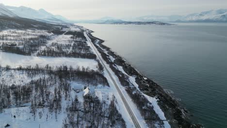 Highway-in-Tromso-Norway-during-winter-in-the-morning-with-snow-near-water