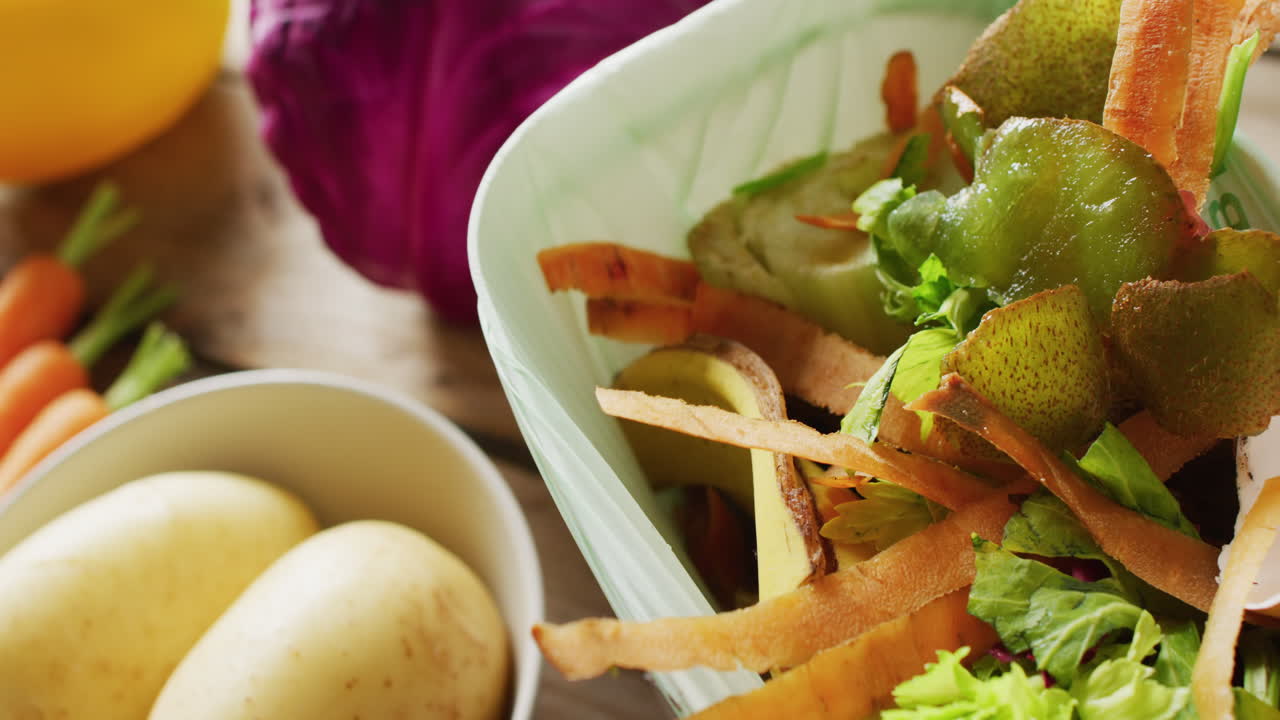 vídeo en primer plano de residuos orgánicos y vegetales en el contenedor de compostaje de la cocina, con verduras detrás