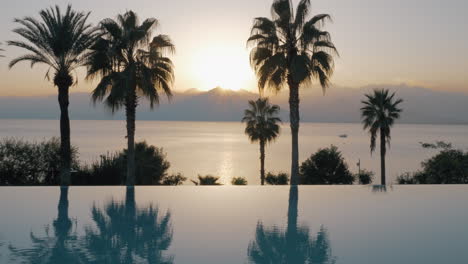 A-steadicam-shot-of-an-open-pool-boundary-and-the-sunset-by-the-sea-behind-it