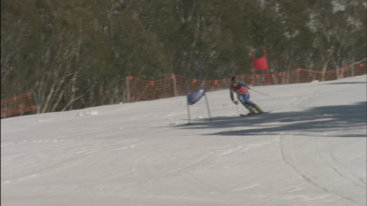 관중들이 지켜보는 가운데 스키 타는 사람이 내리막길에서 스키를 탄다