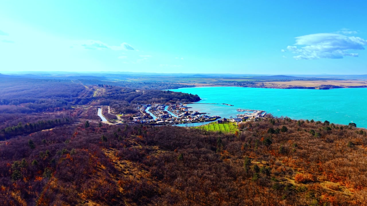 Vista aérea de uma lagoa turquesa e vila de pescadores, Bulgária. Perspectiva de drone de um canal estreito, barcos e telhados coloridos ao longo da costa