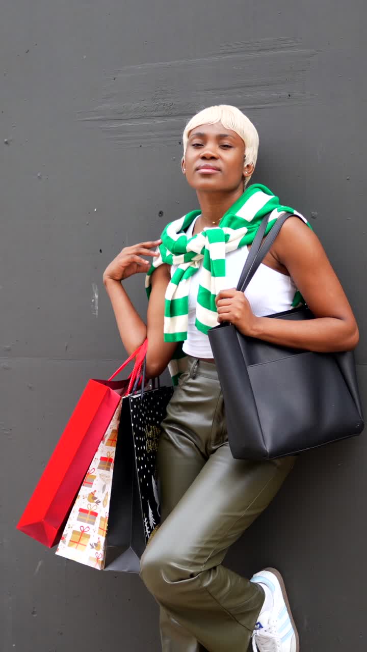 Woman with shopping bags leaning against a wall