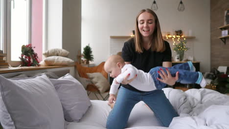 vamos a volar alegre mujer joven hermosa sosteniendo a la niña en sus manos y mirándola con amor mientras está sentada en el sofá en casa
